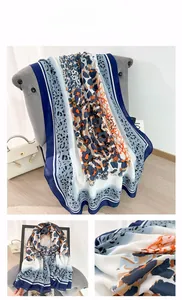 Detail of leopard print scarf featuring orange and grey patterns with blue stripe borders
