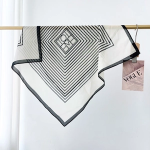 Detail of lightweight black and white geometric silk scarf hanging on a rack