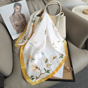 Carré de soie blanc élégant aux motifs de magnolias jaunes drapé sur un sac à main