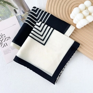 Eleganter schwarz-weiß gestreifter Seidenschal auf einem minimalistischen Holztablett