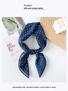 Dettaglio della trama del foulard in seta e cotone blu scuro a pois su sfondo neutro