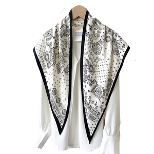 Elegant paisley print silk scarf in off-white with black borders on a wooden hanger
