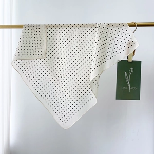 Detalle de un pañuelo de seda con lunares envuelto en una barra dorada con acabado elegante