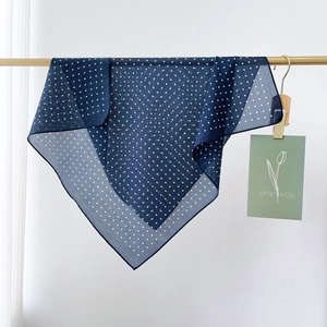 Detalle de un pañuelo azul marino de lunares con textura ligera y caída elegante