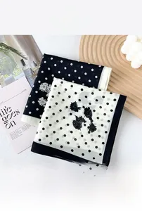 Gros plan d'un foulard en soie et coton à pois noir et blanc avec motifs floraux