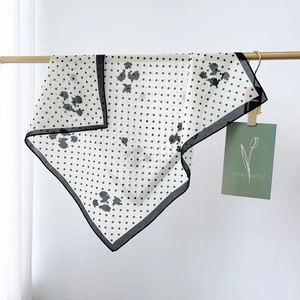 Gros plan d'un foulard en soie à pois et fleurs suspendu à une barre dorée