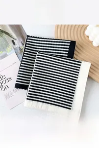 Detail view of black and white striped silk cotton scarves on a minimalist textured surface