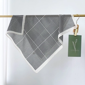 Minimalist black and white striped silk scarf hanging on a gold bar with decor