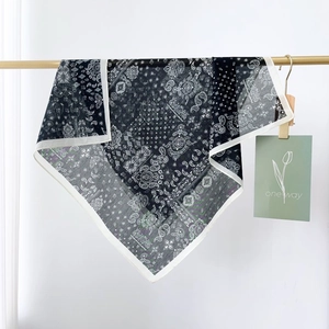 Macro detail of black and white paisley silk scarf hanging on a gold bar with decorative card