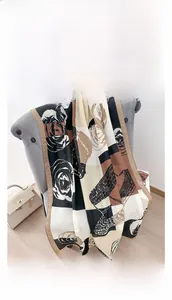 Détail d'une écharpe élégante caramel et noir avec motifs floraux vintage sur un fauteuil