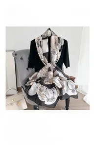 Detail of silk satin scarf featuring camellia print on a mannequin with beige handbag