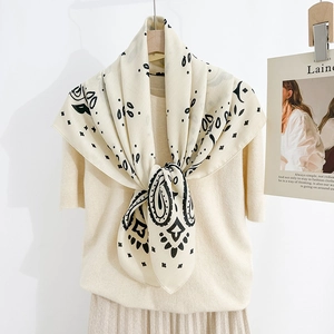 Close-up of beige paisley silk scarf tied around neck with chic knitwear