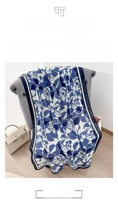 Detailed view of large navy blue rose print linen shawl draped on a modern grey sofa