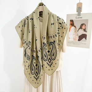 Sage green paisley printed square scarf styled over a beige knit top and pleated skirt