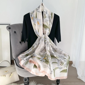 Detailed close-up of a floral print silk scarf featuring elegant pastel flower patterns