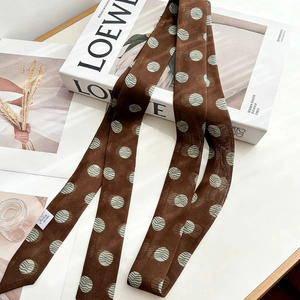 Brown 100% mulberry silk narrow scarf with green polka dots on decorative luxury book