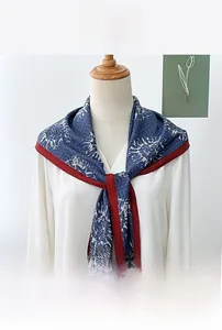 Dettaglio foulard a triangolo blu scuro a fiori con bordo rosso su top bianco