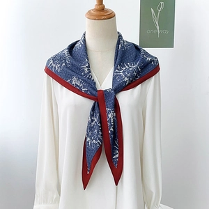 Dettaglio di sciarpa stampata blu navy e bordeaux annodata su una camicia bianca