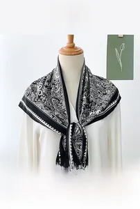 Detail of paisley pattern black and white silk-like triangular scarf on a mannequin