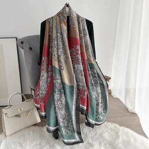 Detailed macro view of the elegant paisley print and silky fabric texture on the long shawl