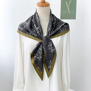 Dettaglio foulard in seta grigia con stampa floreale e bordo verde oliva su camicia bianca