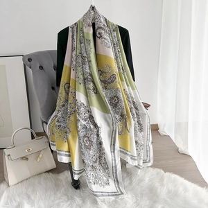 Close-up of lightweight silk shawl with intricate green and yellow paisley floral patterns