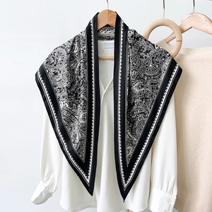 French style paisley silk scarf in black and white hanging on a wooden hanger