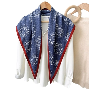 Sciarpa blu stampata con bordo rosso su camicia bianca appesa a stampella in legno