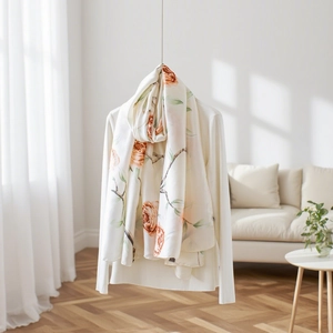 Dettaglio di una sciarpa di seta crema con stampe di rose arancioni e drappeggio elegante