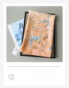 Detail of thin orange-pink scarf showing delicate lily floral print on soft fabric