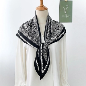 Elegant black and white paisley silk scarf with leaf patterns on a white blouse mannequin