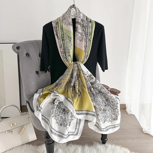 Elegant paisley print silk scarf in green and yellow draped on a mannequin