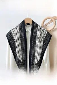 Detail of polka dot printed triangle scarf with black piping on a wooden hanger
