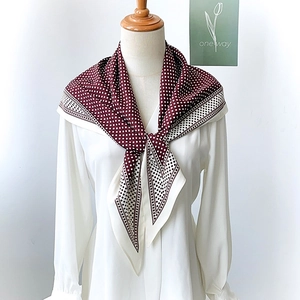Elegant burgundy polka dot silk scarf tied on a white shirt for a classic French vintage look