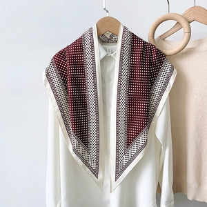 Close-up of a burgundy polka dot silk scarf draped over a white shirt on a wooden hanger