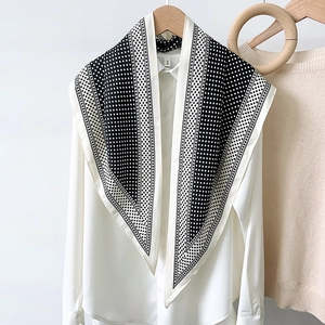 Polka dot silk scarf with black borders styled on a white shirt with a wooden hanger