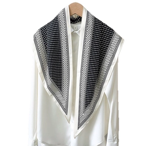 Elegant black and white polka dot silk scarf draped over a classic white shirt for office wear