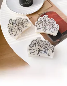 Detalle de pinza para el pelo de acetato blanco perlado con diseño de lirio y pedrería fina