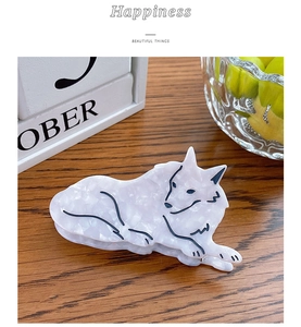 Detailed view of animal-shaped hair claw clip in marbled acetate on a wooden desk