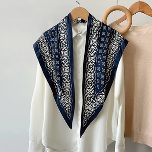 Navy and white geometric totem silk scarf draped elegantly over a white shirt