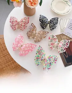 Détail de six pinces à cheveux papillon aux motifs et couleurs variés sur une table