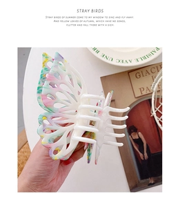 Vue détaillée de la grande pince à cheveux papillon en acétate blanc avec taches colorées