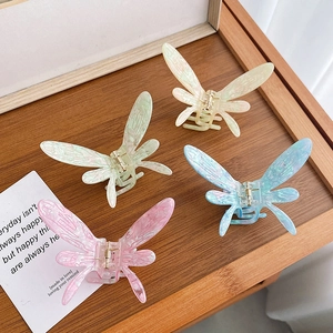 Pinces à cheveux papillon élégantes en acétate pastel sur un plateau en bois vintage