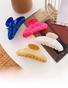 Detail of four colorful acetate hair claws with marble texture and wavy pattern