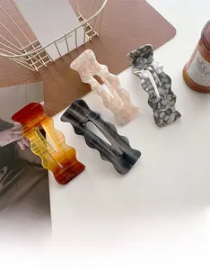 Macro shot of oversized acetate hair clips featuring elegant wavy textures and marble patterns