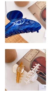 Detailed view of large marble texture acetate hair claws in blue, amber, and pearl white