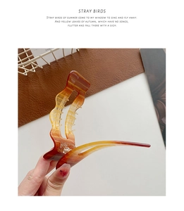 Close-up of oversized amber acetate hair claw clip with irregular wavy design