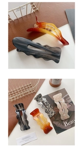 Macro view of long acetate hair clips with amber marble patterns and wavy edge details