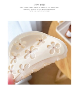 Detailed view of cream acetate flower hair claw with sparkling rhinestone centers