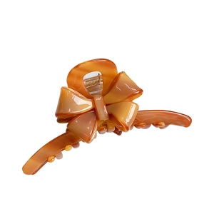 Large amber acetate bow hair claw clip with glossy finish and durable metal spring